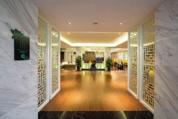 A hotel lobby with a marble reception desk, wooden flooring, and decorative panels.