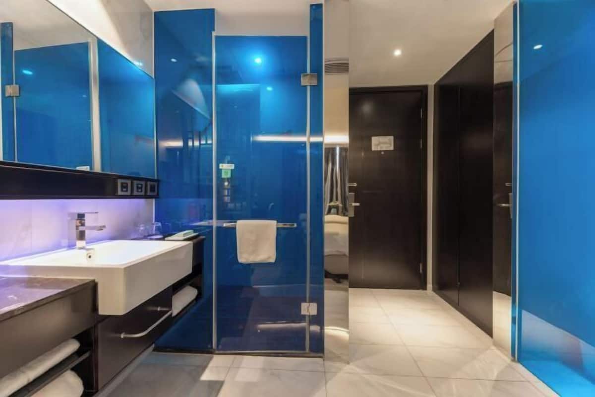 Un baño moderno con cabina de ducha de vidrio, lavabo blanco y tocador de tonos oscuros.