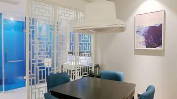 A dining area with a table and chairs, a decorative partition, and a wall-mounted air conditioning unit.