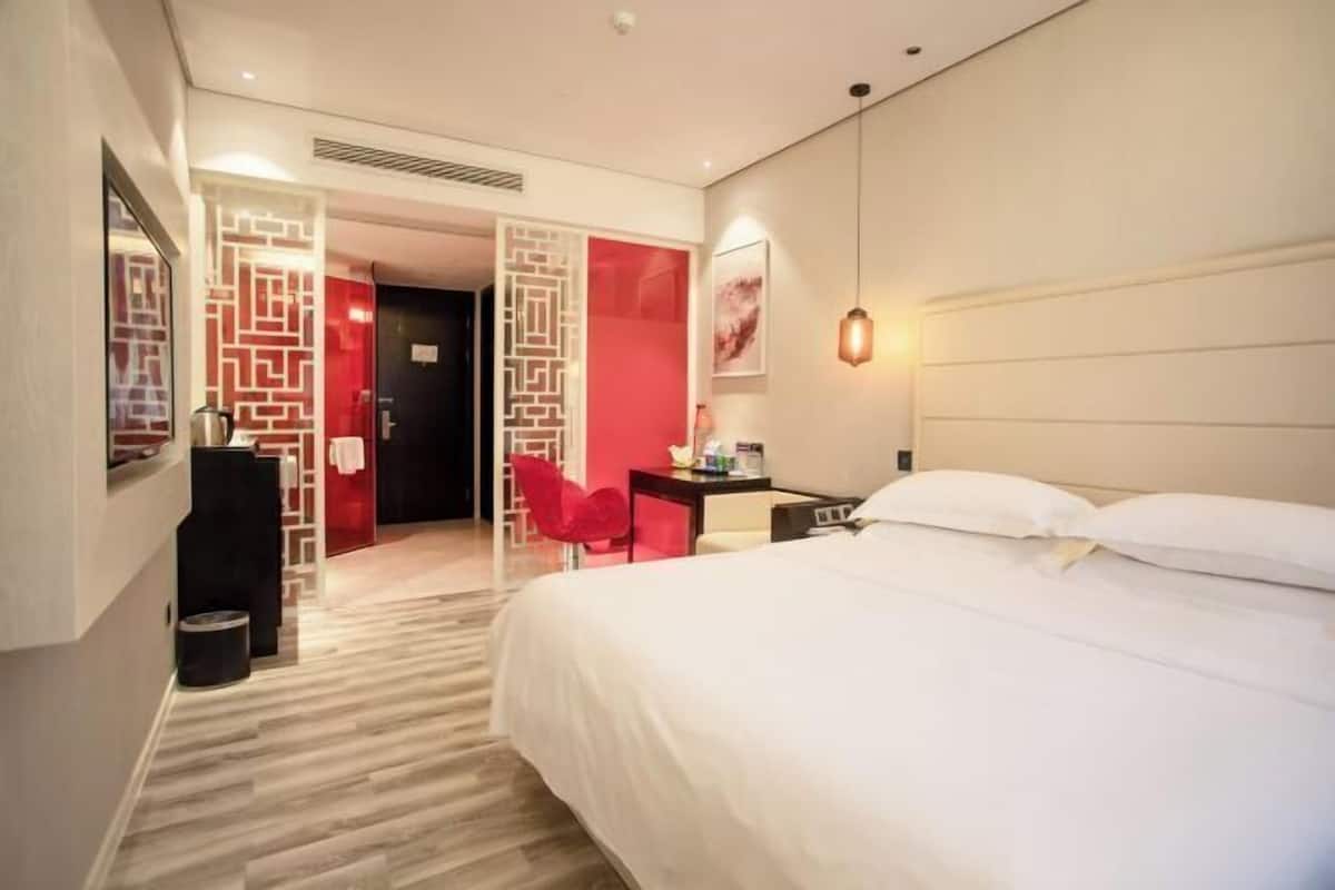Una habitación de hotel con una cama, un escritorio, una silla y una pared decorada en rojo.