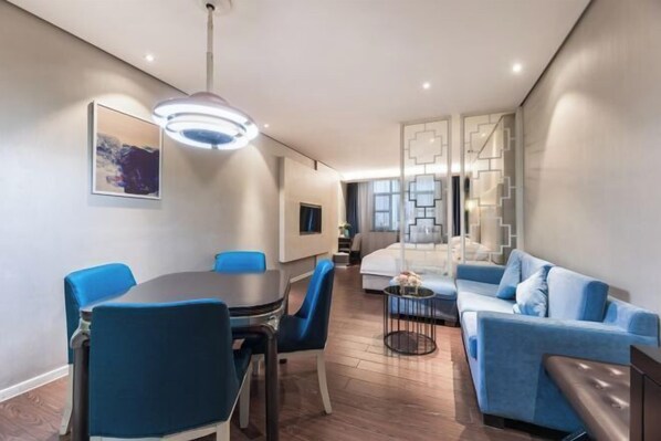Ein modernes Hotelzimmer mit Essbereich, einer Couch, einem Bett und einer dekorativen Wandverkleidung.