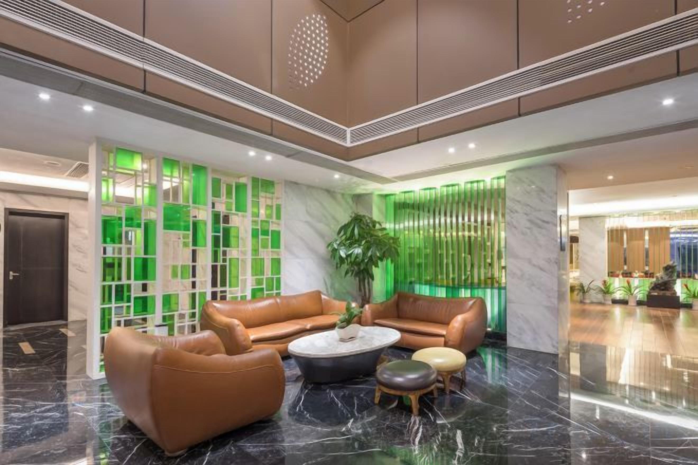 A lobby with leather sofas, a coffee table, and a potted plant.