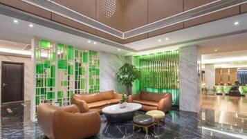 A lobby with leather sofas, a coffee table, and a potted plant.