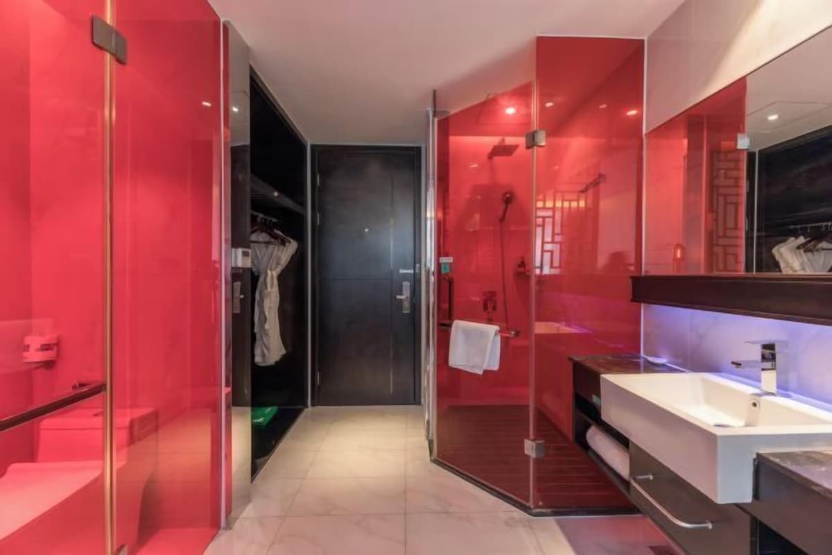 Ein modernes Badezimmer mit einer Duschkabine, einem Waschtisch mit Spiegel und einem begehbaren Kleiderschrank.