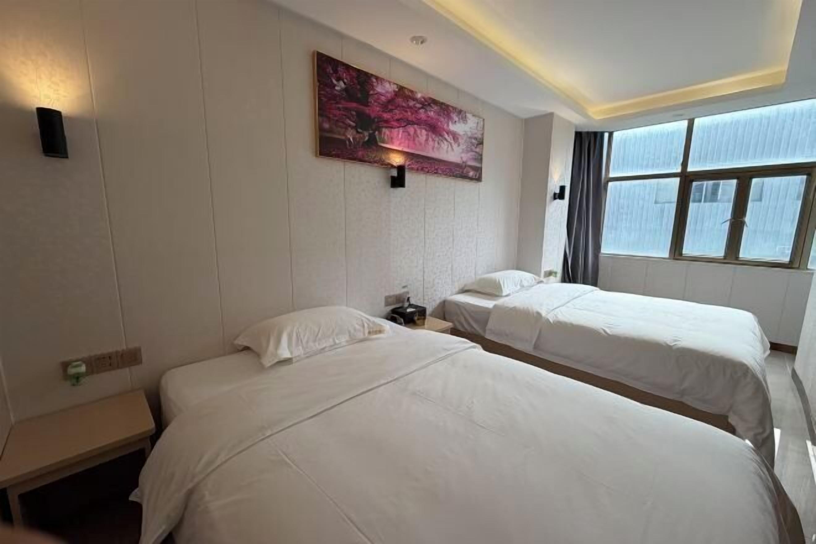 Hotelkamer met twee bedden, een nachtkastje, een schilderij en een raam met gordijnen.