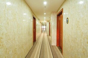 Un pasillo de hotel con paredes de mármol, puertas de madera y una alfombra a rayas.