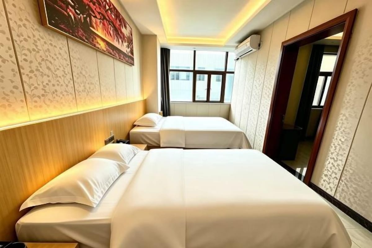 A hotel room with two beds, a large window, and a mirror.