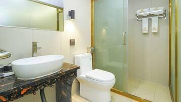 A bathroom with a white sink, a toilet, and a glass shower enclosure.