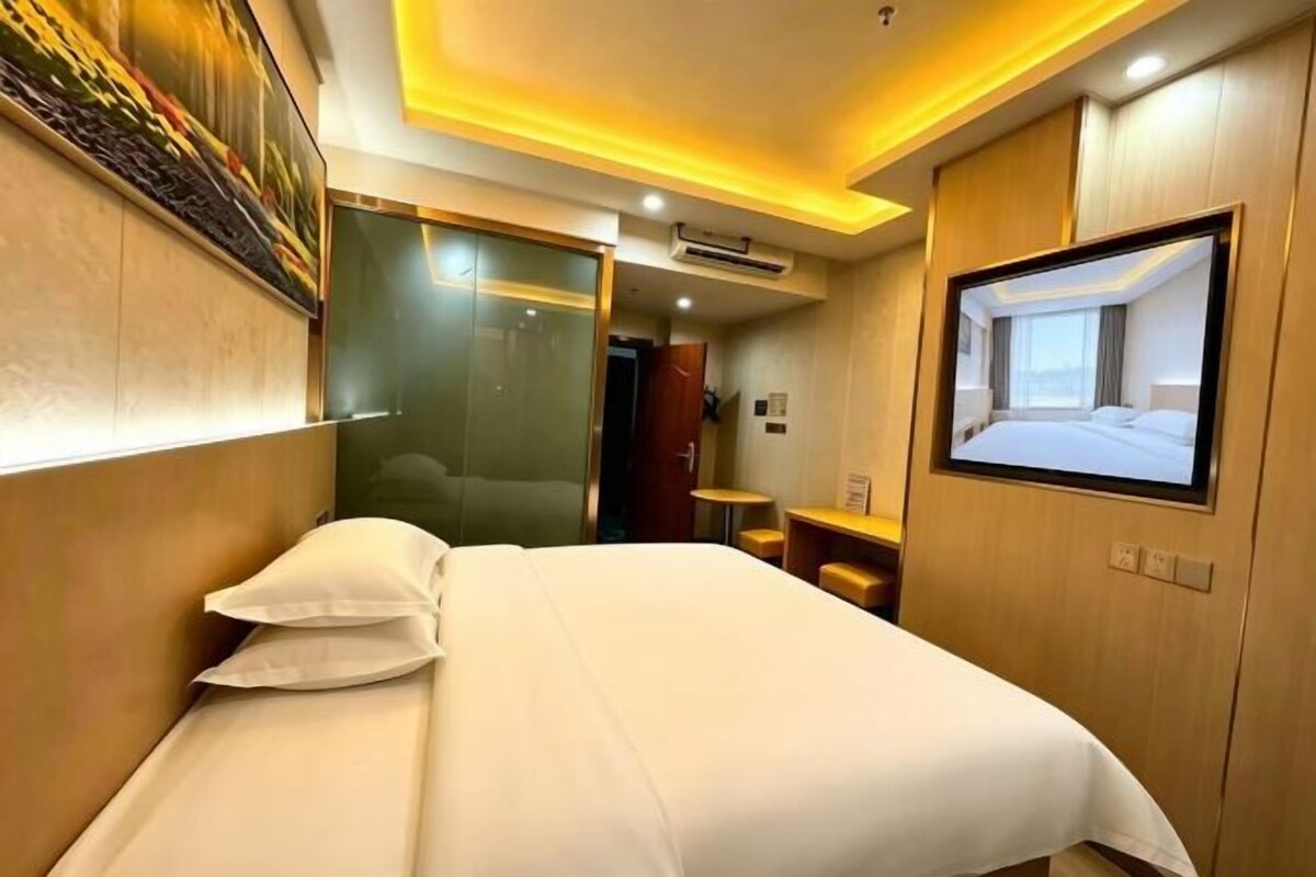 A hotel room with a bed, a television, and a mirror.