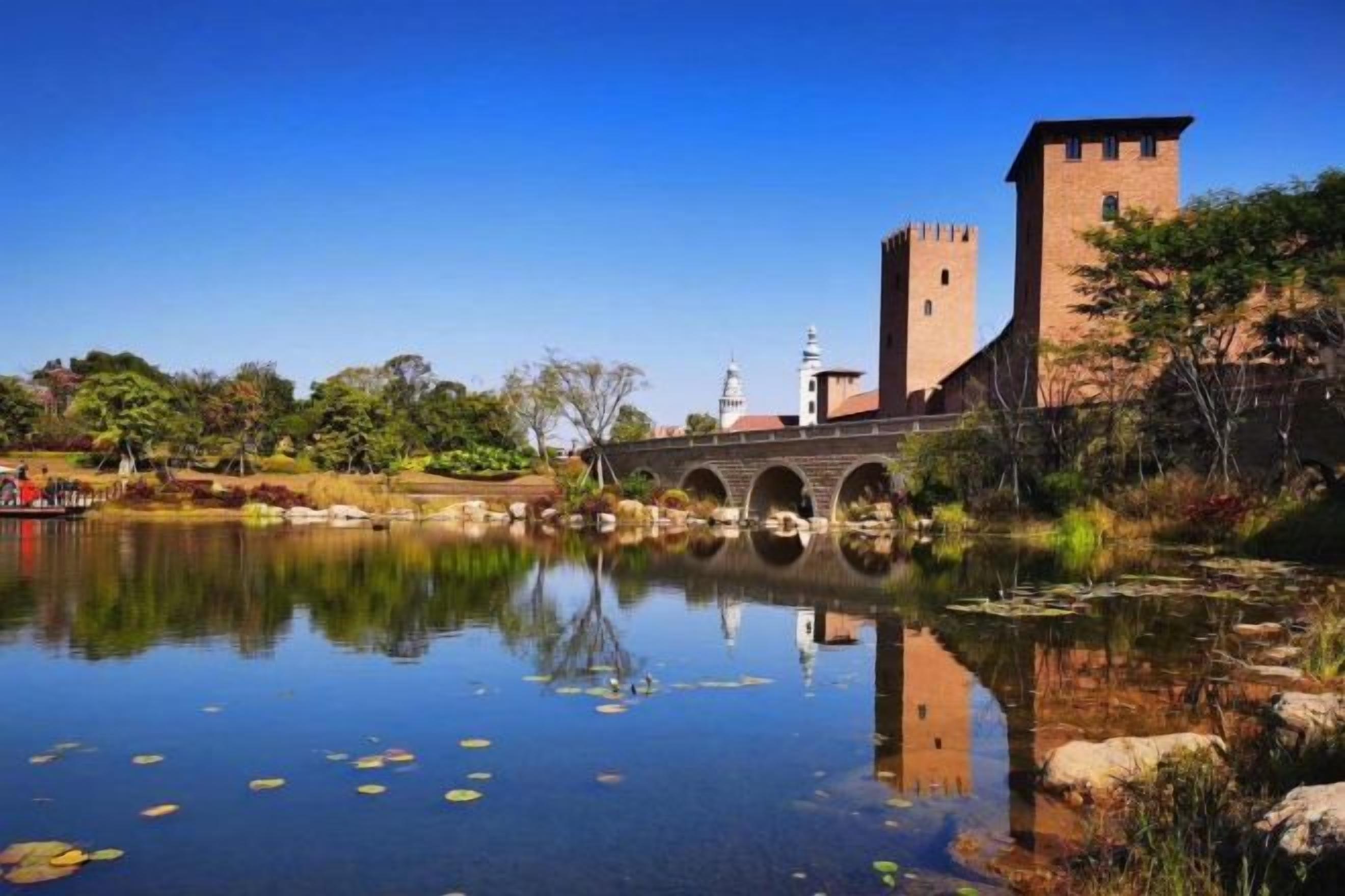 A historic building with a tower and arched bridge over a calm body of water.