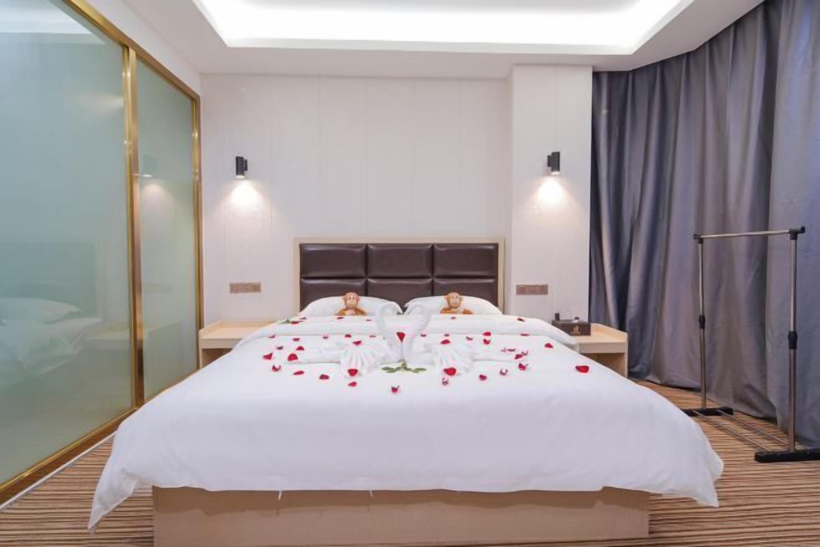 Une chambre d’hôtel avec un grand lit, des tables de chevet, une tête de lit et un rideau d’un côté.