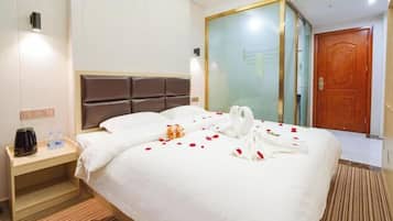 A hotel room with a large bed, a bedside table with a coffee maker, and a wardrobe with a glass door.