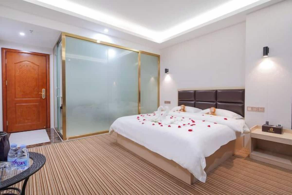 A hotel room with a bed, bedside table, and a glass partition door.