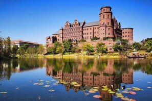 A large, historic building with a reflection in a calm body of water, surrounded by greenery. - City Convenient Hotel (Dongguan)