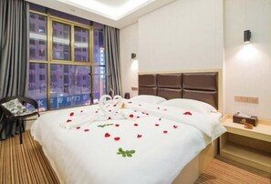 Habitación de hotel con una cama grande, una mesita de noche, una silla y una ventana con cortinas.