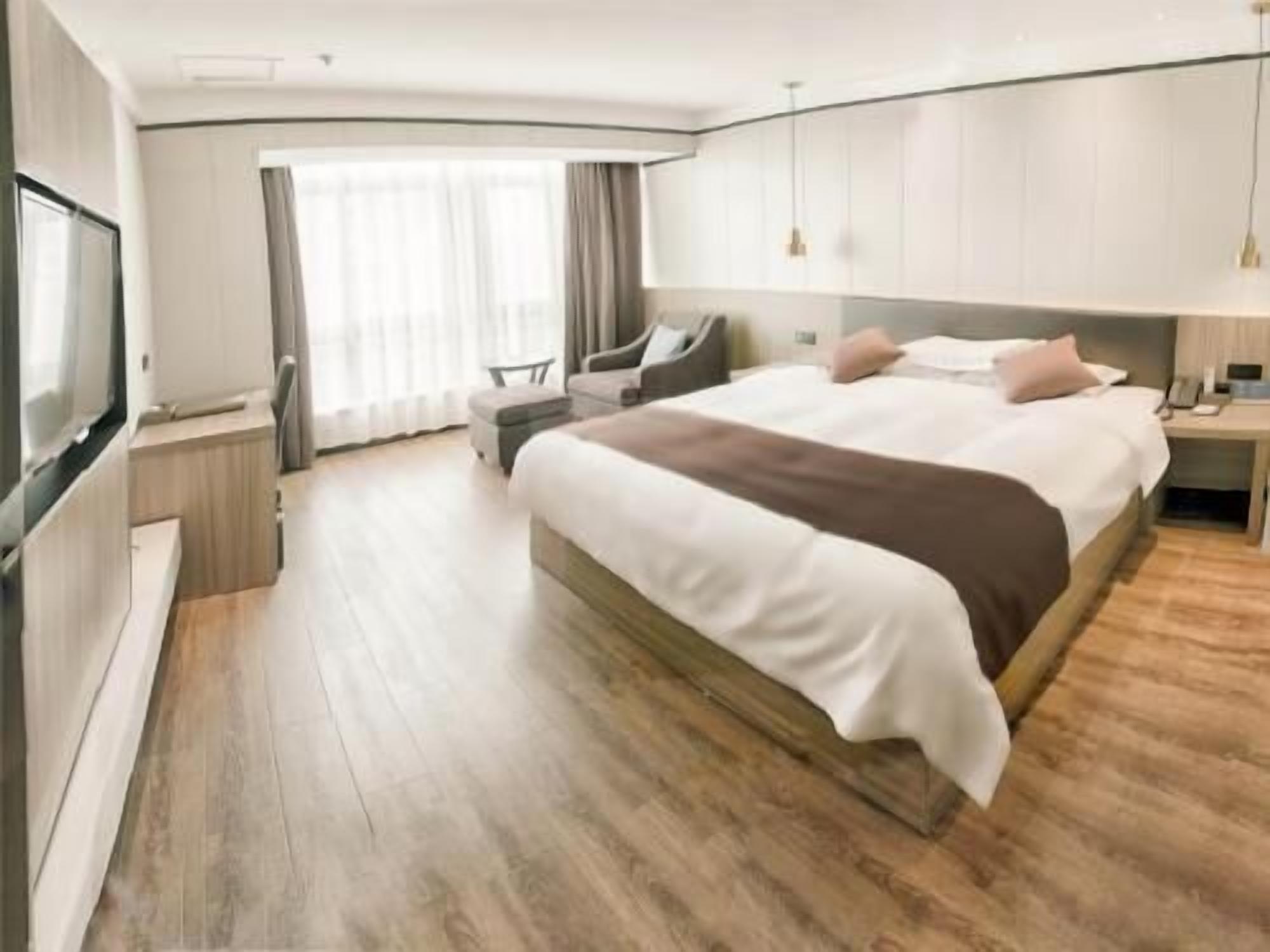 Habitación de hotel moderna con una cama grande, televisor, escritorio y silla.