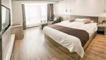 Habitación de hotel moderna con una cama grande, televisor, escritorio y silla.