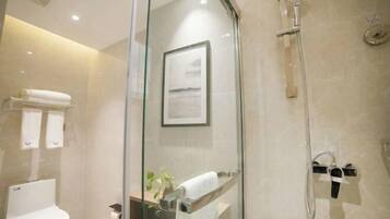 Un baño moderno con cabina de ducha de vidrio, inodoro y un cuadro enmarcado en la pared.