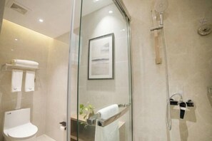 A modern bathroom with a glass shower enclosure, a toilet, and a framed picture on the wall. - GYA Hotel (Yancheng Wengang Road High-speed Railway Station) (Yancheng)