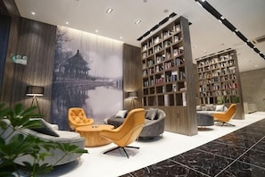 Un hall d’entrée moderne, doté de sièges, de bibliothèques et d’une grande fresque murale.