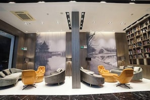 Un hall d’entrée avec des coins salon, une bibliothèque et une grande fresque murale.