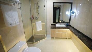 Un baño moderno con ducha envuelta en vidrio, inodoro blanco, lavamanos con encimera de mármol y espejo con iluminación.