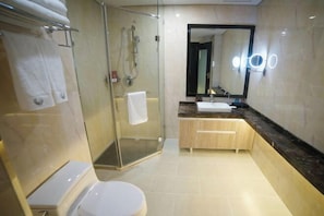 A modern bathroom with a glass-enclosed shower, a white toilet, a sink with a marble countertop, and a mirror with lights. - GYA Hotel (Yancheng Wengang Road High-speed Railway Station) (Yancheng)