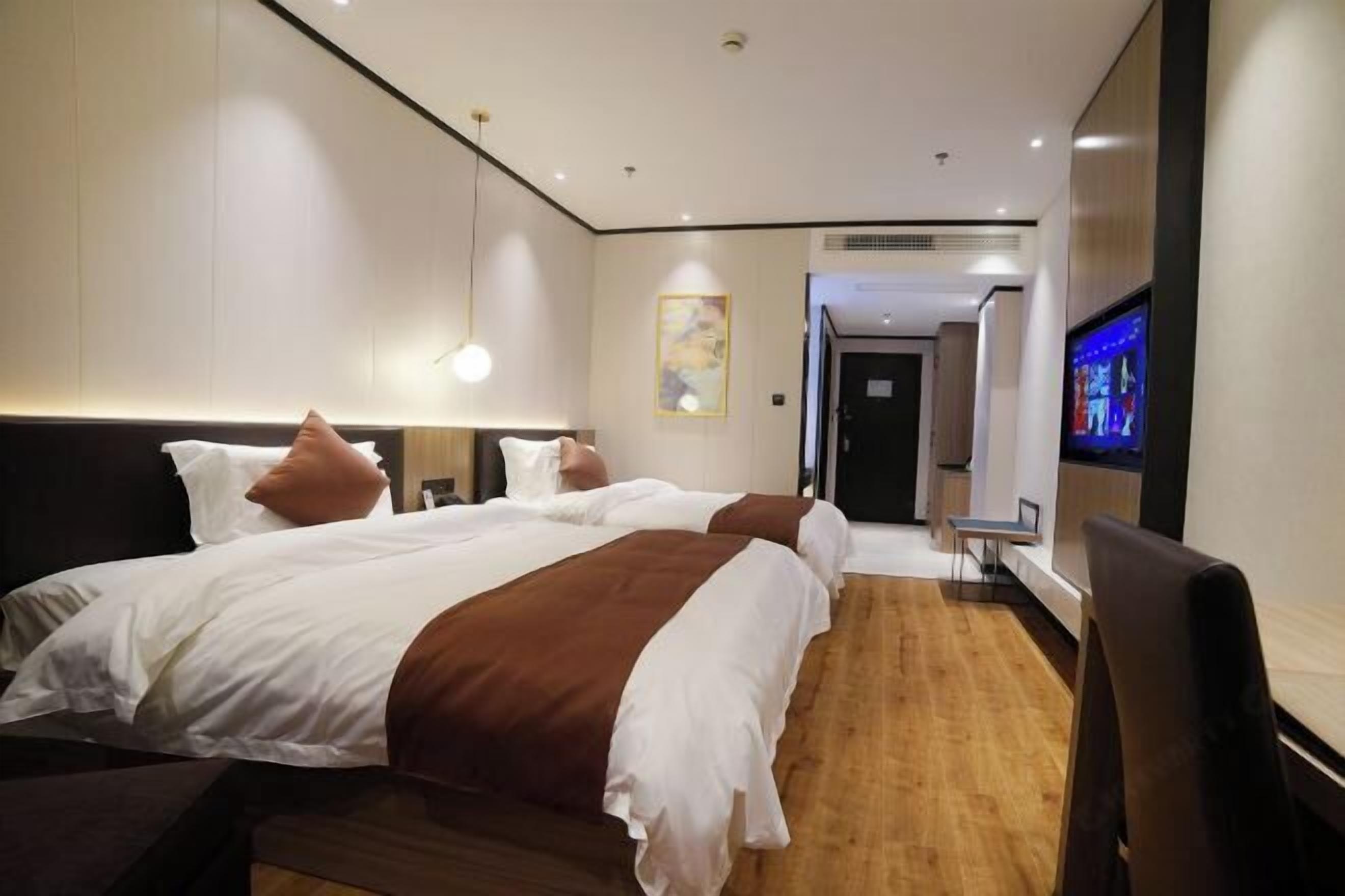 Una habitación de hotel con una cama grande, mesitas de noche, televisión y suelo de madera.