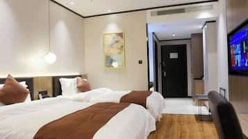 Habitación de hotel con dos camas, un escritorio, un televisor y un cuadro en la pared.
