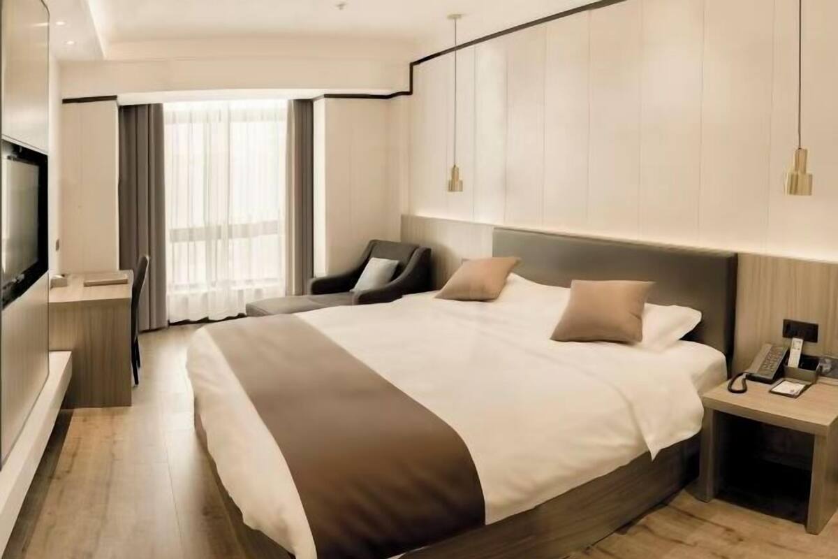 A modern hotel room with a large bed, a desk, and a TV.
