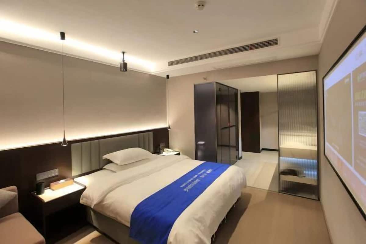A hotel room with a bed, bedside table, and a large mirror.