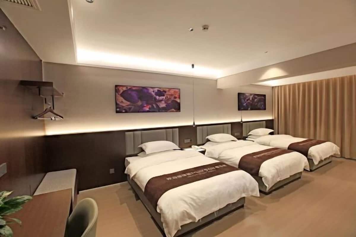 A hotel room with a large bed, a desk, and a chair.