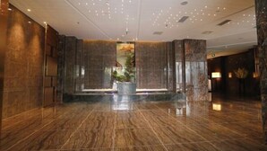Eine großzügige Lobby mit poliertem Marmorboden, einer zentralen Wasserspüle und einem großen Wandgemälde.