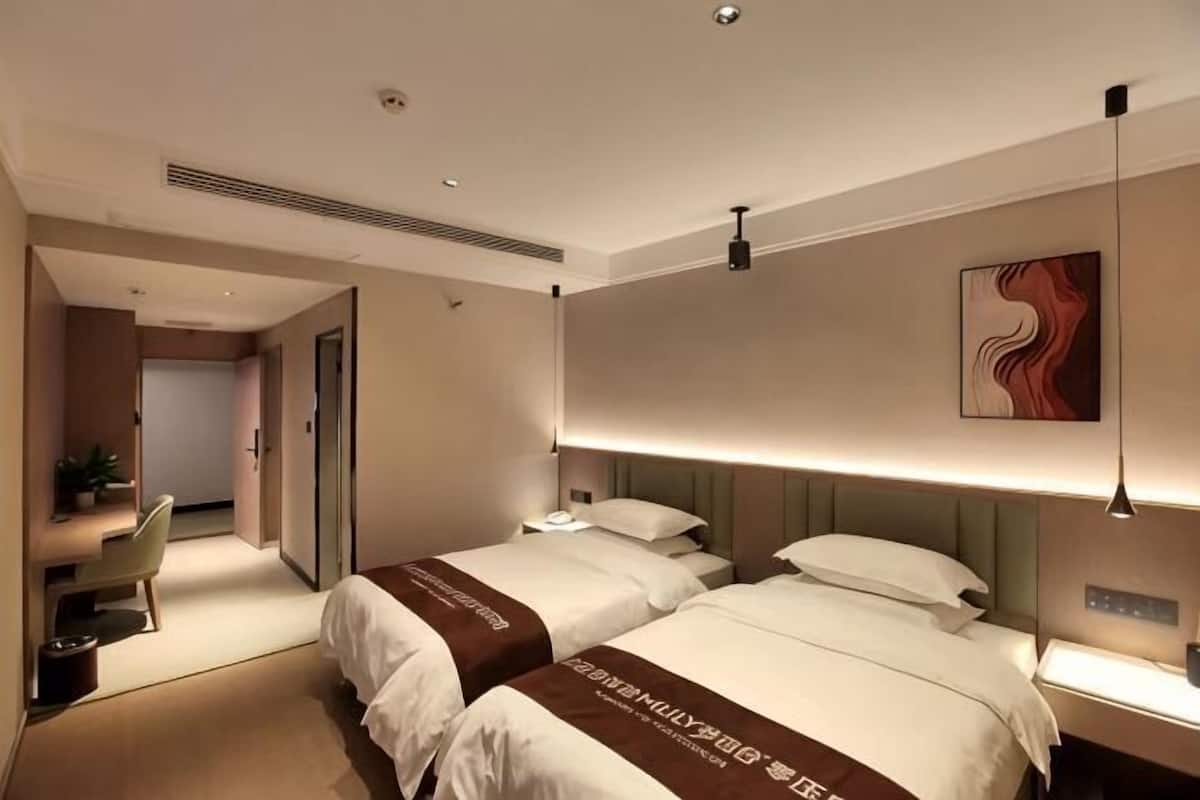 A hotel room with two beds, a desk, and a chair.