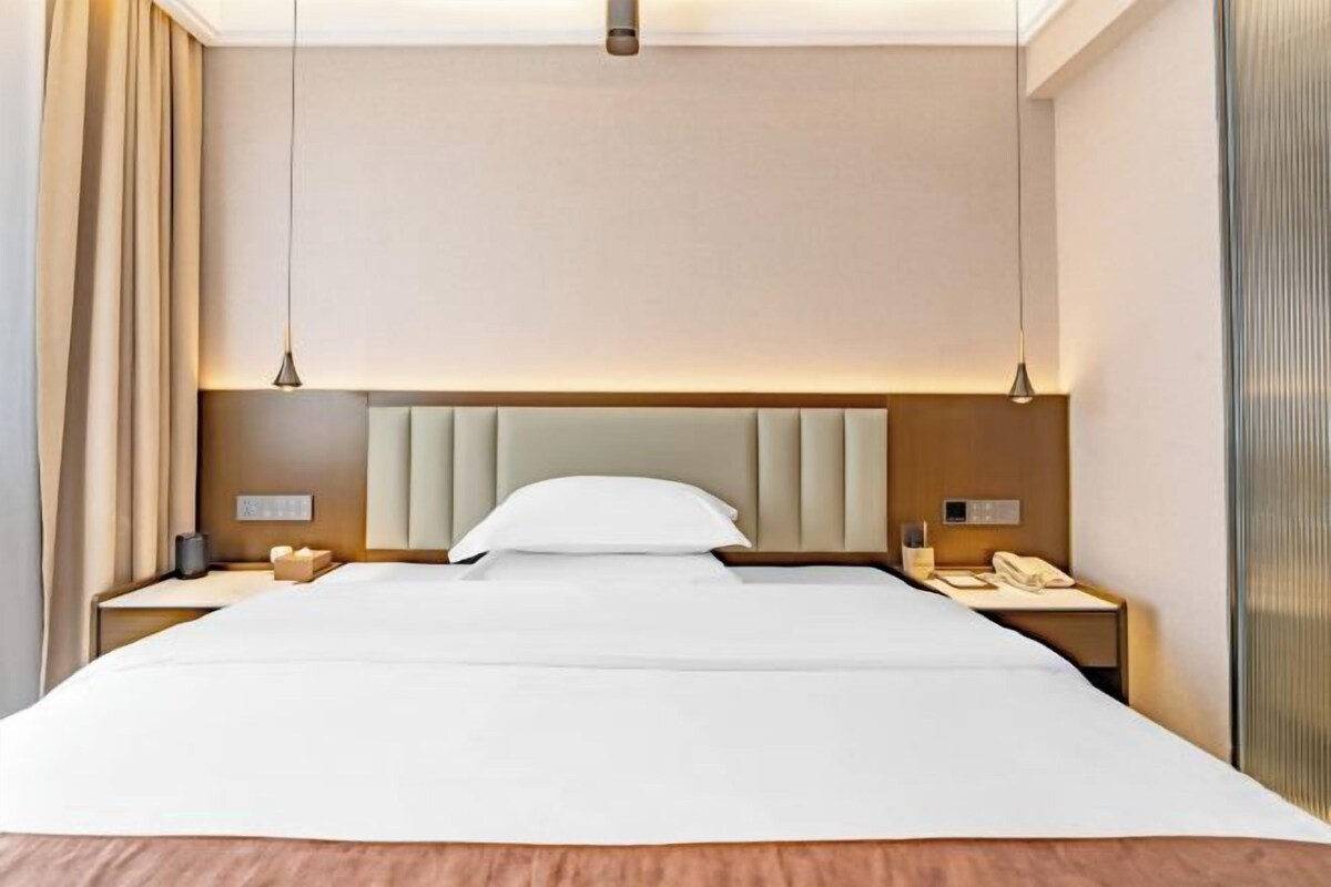Een hotelkamer met een groot bed, twee nachtkastjes, een hoofdeinde en een nachtkastje met een lamp.