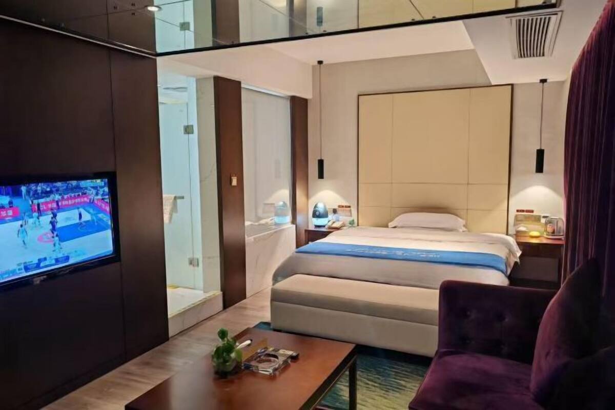 A hotel room with a bed, a television, a desk, and a chair.