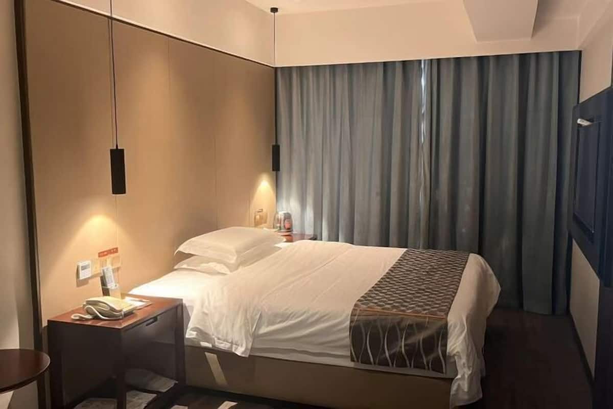 A hotel room with a bed, bedside tables, a telephone, and a curtain.