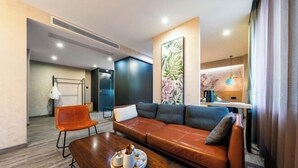 Una habitación de hotel moderna con un sofá de cuero, una mesa de centro de madera y una obra de arte floral grande en la pared.