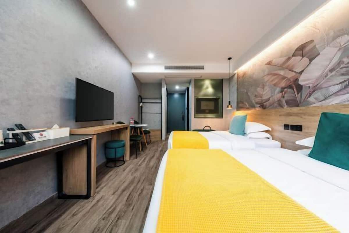 Una habitación de hotel con cama, escritorio, televisión y un mural en la pared.