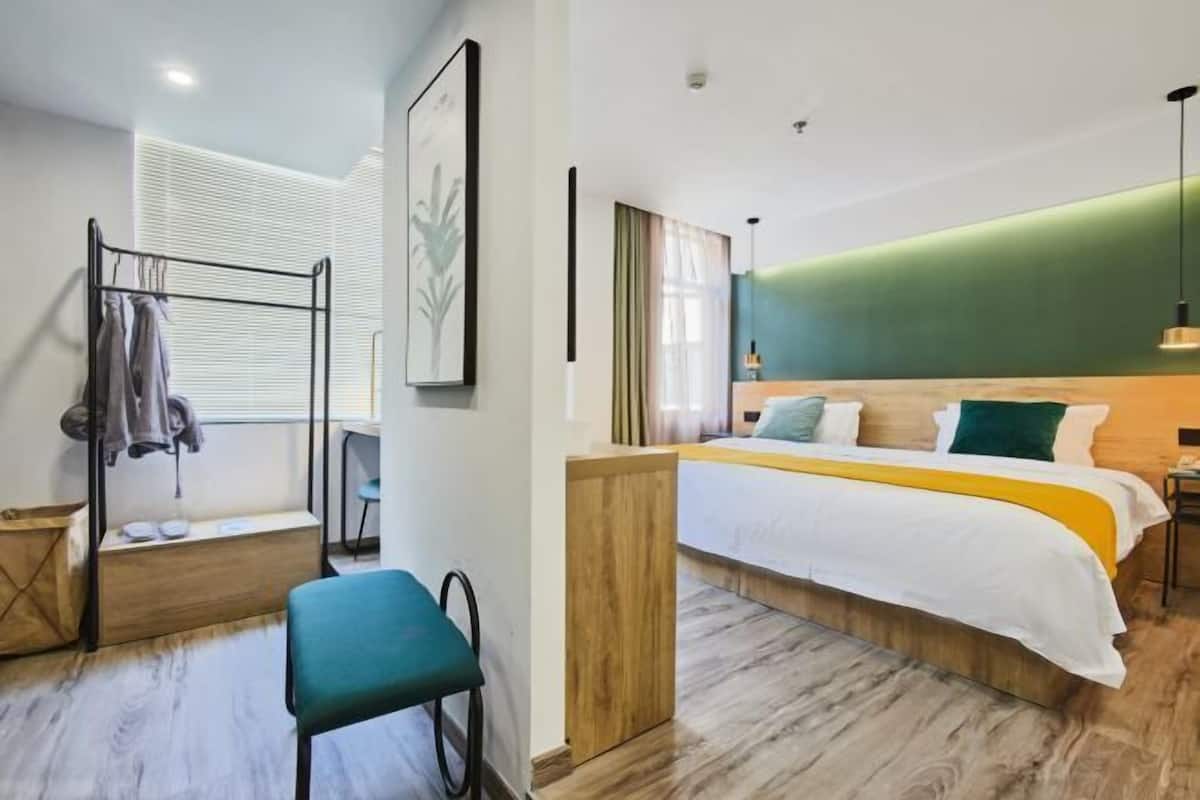 Una habitación de hotel moderna con una cama, un área de descanso y un ventanal con persianas.