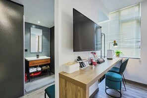A modern hotel room with a wooden desk, a flat-screen TV, a large mirror, and a window with blinds. - Leaf Time Art Hotel (Hangzhou)