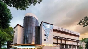Un edificio moderno con una estructura cilíndrica destacada y un gran logotipo en la fachada.