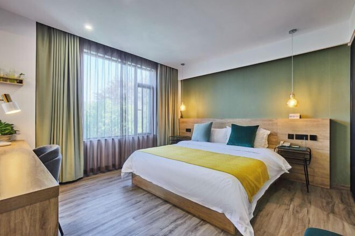A modern hotel room with a large bed, a desk, and a view of the outdoors.