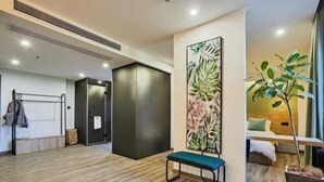 Habitación de hotel moderna con suelo de madera, un banco, una obra de arte floral grande en la pared y una planta en maceta.
