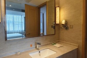 A hotel bathroom with a large mirror, a sink, and a vanity.