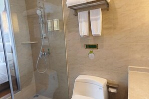 A bathroom with a glass-enclosed shower, a toilet, and a towel rack with towels.