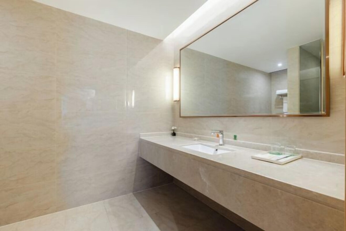 A modern bathroom with a large mirror, two sinks, and a vanity.