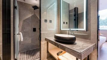 Une salle de bain moderne avec une douche à l’italienne en verre, un lavabo en marbre et un grand miroir.