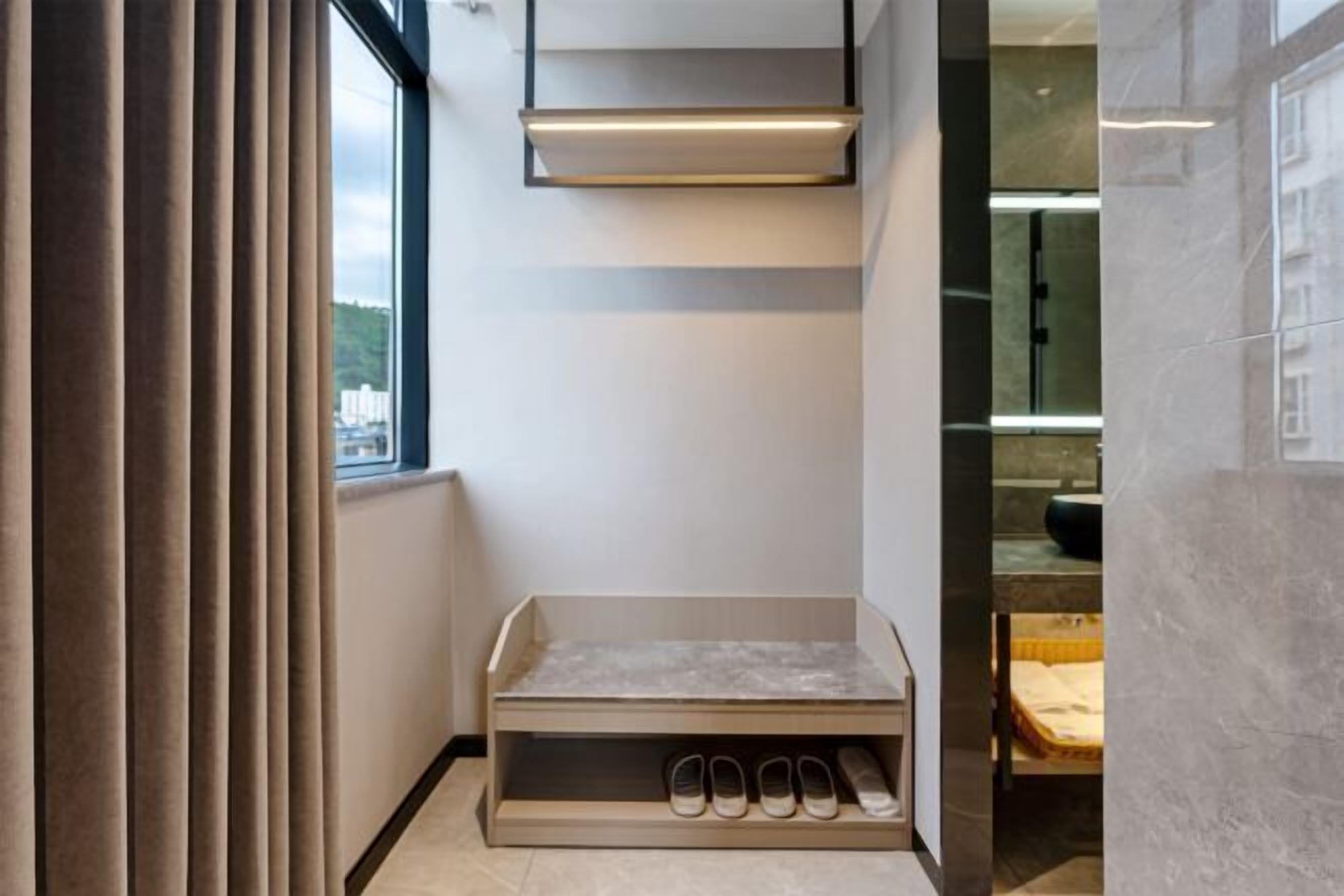 A modern bathroom with a built-in shoe rack and a large window.