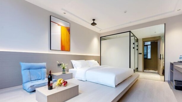 Ein modernes Hotelzimmer mit Bett, einer Sitzecke mit Tisch und einer Glastrennwand.